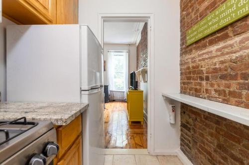 a kitchen with a white refrigerator and a brick wall at Apartment 1411: Fort Greene in Brooklyn