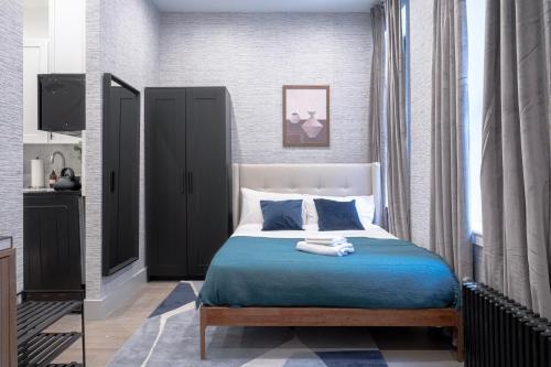 Schlafzimmer mit einem Bett mit blauer Bettwäsche und einem Fenster in der Unterkunft Apartment 256: Upper West Side in New York