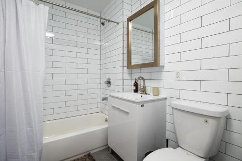 a white bathroom with a toilet and a sink and a tub at Apartment 235: Lower East Side in New York