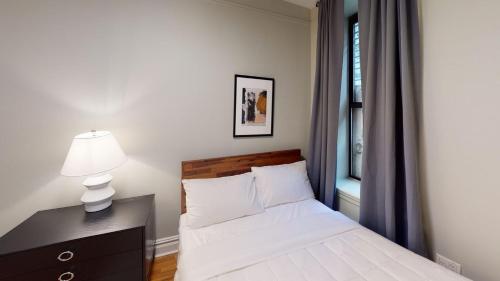 ein Schlafzimmer mit einem Bett mit einer Lampe und einem Fenster in der Unterkunft Apartment 549: Upper West Side in New York