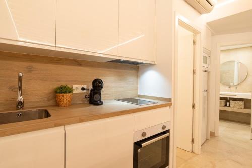 una cocina con armarios blancos y fregadero en Lazcano & old town by ELE Apartments, en Málaga