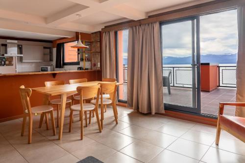 a kitchen and dining room with a table and a balcony at Belgrano Decks II in San Carlos de Bariloche