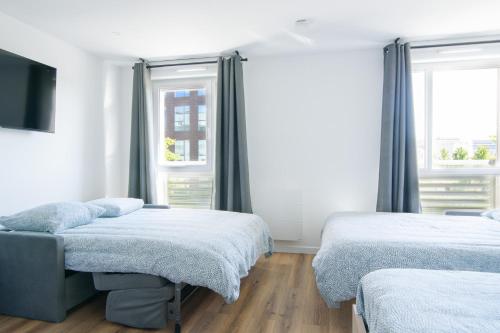 deux lits dans une chambre avec deux fenêtres dans l'établissement Studio Disneyland RER 6 pers, à Montévrain
