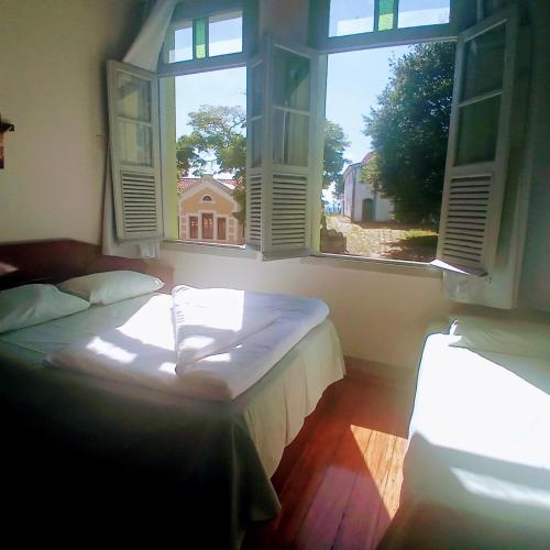 a bedroom with two beds and two windows at Pousada Gameleira in Diamantina