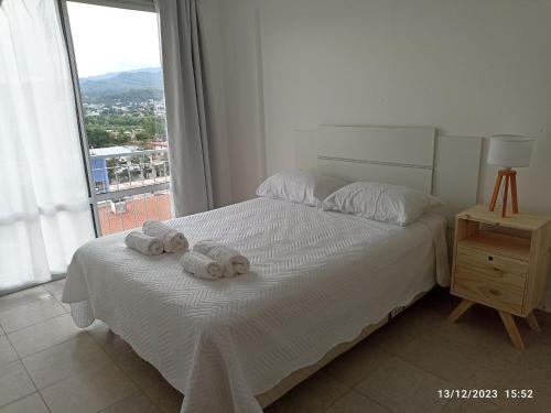 Un dormitorio con una cama blanca con toallas. en Los Juncos Jujuy en San Salvador de Jujuy