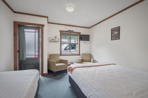 une chambre d'hôtel avec deux lits et une chaise dans l'établissement Punakaiki Rocks Hotel & Garden Bar, à Punakaiki