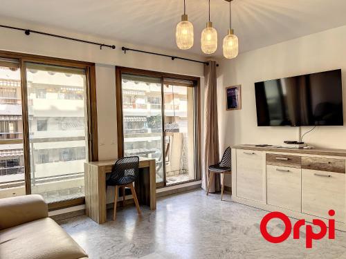 - un salon avec une télévision et un bureau avec des chaises dans l'établissement Appartement climatisé avec terrasse, centre-ville de Menton, à deux pas des plages - FR-1-647-24, à Menton