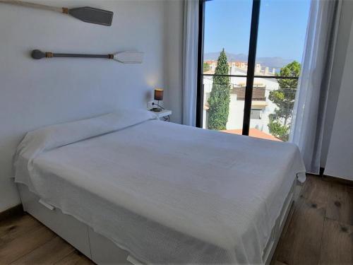 un letto bianco in una stanza con una grande finestra di Apartamento Llançà, 1 dormitorio, 4 personas - ES-170-74 a Llança