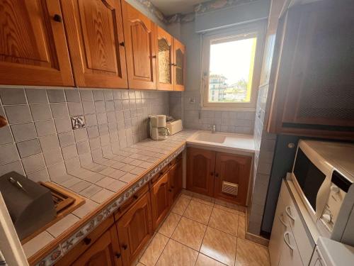Elle comprend une petite cuisine avec des placards en bois et une fenêtre. dans l'établissement Appartement 2 pièces proche plage avec garage, Fréjus - FR-1-226A-167, à Fréjus