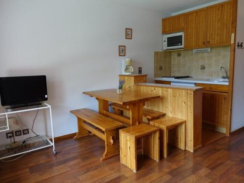 une cuisine avec une table en bois avec des bancs et une télévision dans l'établissement Studio cabine ski et rando, 4 pers, pied des pistes, Arêches-Beaufort - FR-1-342-313, à Beaufort