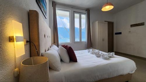 una camera da letto con un grande letto bianco con una grande finestra di San Pedro Suite a San Pedro La Laguna