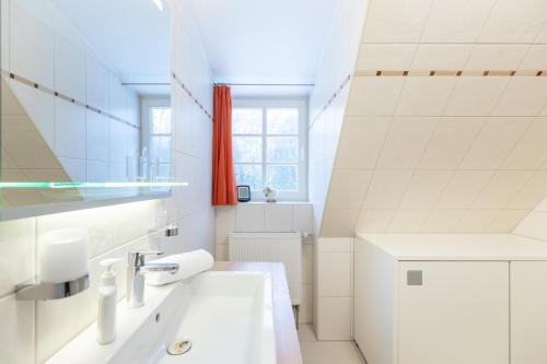 a white bathroom with a sink and a window at Salzwiesen-Lodge in Westereck
