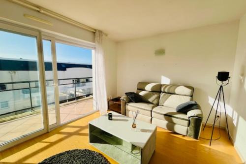 uma sala de estar com um sofá e uma grande janela em Charming love nest with balcony em La Rochelle