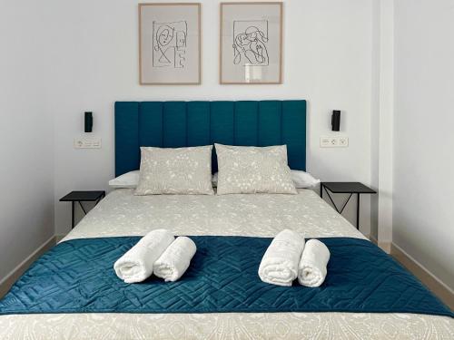 a bed with a blue headboard and two white pillows at Picú Home in Málaga
