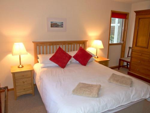 a bedroom with a large white bed with red pillows at Balorrin in Contin