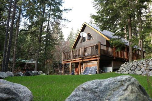 a large log cabin in the woods with rocks at Alpine Retreat: Off-Grid Cabin Winter Adventure in Pemberton
