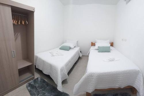 two beds in a room with white sheets and blue pillows at Beatiful apartment in condo in Girardot