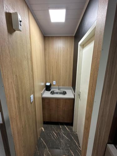 ein Badezimmer mit einem Waschbecken und einer Holztür in der Unterkunft Loft Lux 1 in Chapecó
