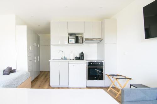 une cuisine avec des armoires blanches et une cuisinière dans l'établissement Studio Disneyland RER 6 pers, à Montévrain