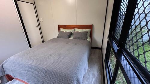 a small bed in a room with a window at Feng Shui Sugarcane Cabin in Proserpine
