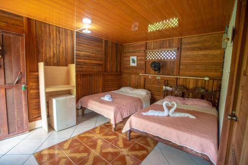 two beds in a room with wooden walls at Tío Felix Eco Lodge in Fortuna