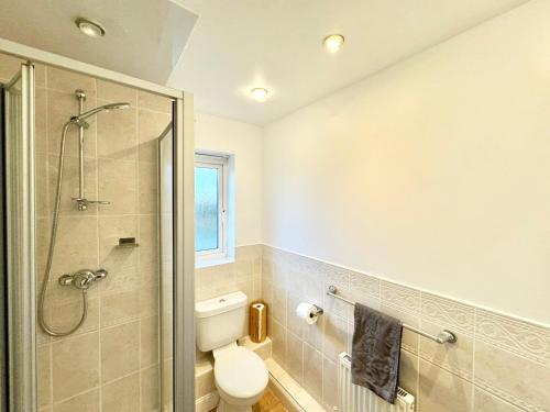 a bathroom with a toilet and a glass shower at 4 bedroom home just off the M20 easy access to Dover & Eurotunnel central Ashford & parking in Ashford