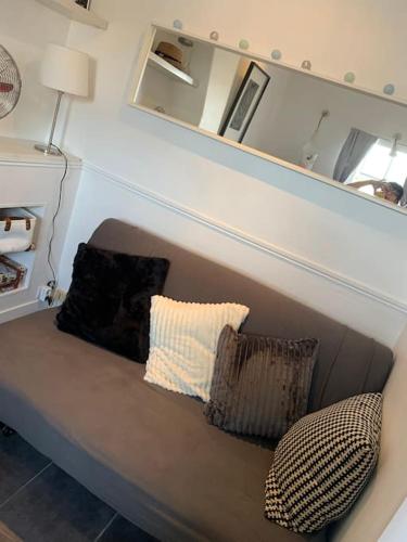 - un canapé avec deux oreillers assis sous un miroir dans l'établissement STUDIO CŒUR VIEUX PARIS. Pied du métro.Tout équipé, à Paris