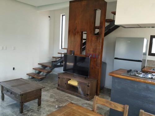 a living room with a flat screen tv and a kitchen at PISÓN PDD in Punta Del Diablo