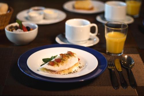 a table with a plate of food and a cup of orange juice at Ilha de Toque Toque Eco Hotel in São Sebastião