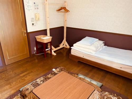 a small room with a bed and a table at Guest House Nishiborakan in Gujo