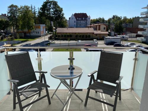 a glass table and two chairs on a balcony at Apartament 33 Nad Iławką in Iława