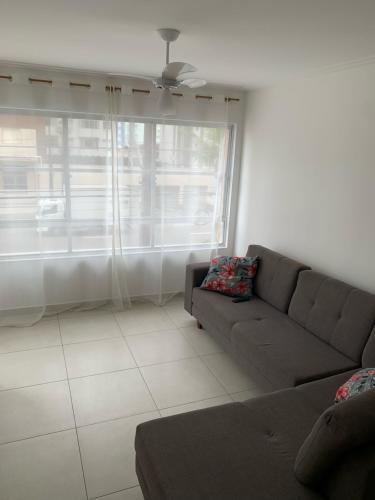 a living room with a couch and a large window at Apto frente Praia Itararé in São Vicente