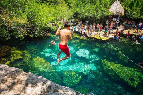 a young man jumping into a pool of water at Marina Haven Rooftop Jacuzzis Prvt Dock BBQ & Pool in Puerto Aventuras