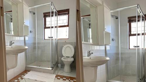 a bathroom with two sinks and a toilet and a shower at Kabana Family Home and Guest House in Cape Town