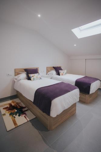 two beds sitting in a room at Casas del Pedregal apartamento 3 in A Estrada