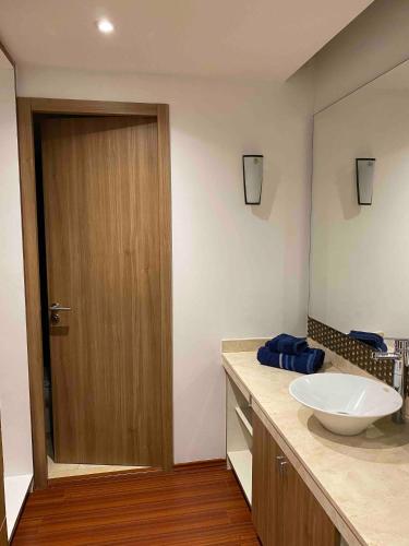 a bathroom with a sink and a wooden door at Beautiful Apartment Reforma77 22thfloor 1bdr 2bath in Mexico City
