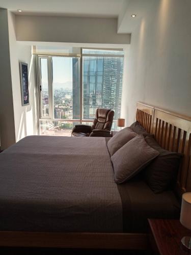 a bedroom with a bed and a chair and a window at Beautiful Apartment Reforma77 22thfloor 1bdr 2bath in Mexico City