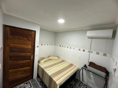 Habitación pequeña con cama y puerta en Casa - Peroba, en Maragogi