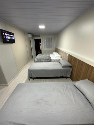 a room with two beds and a flat screen tv at Loft Lux 3 in Chapecó