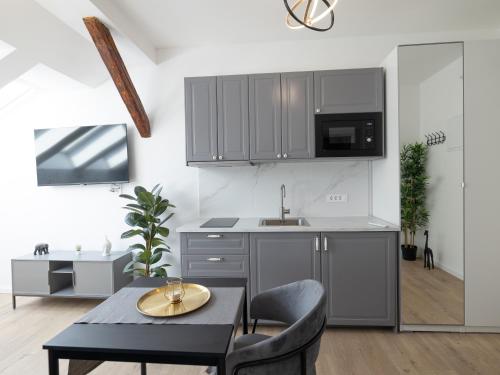a kitchen with gray cabinets and a table and chairs at Zagreb City Center Apartments LUX in Zagreb