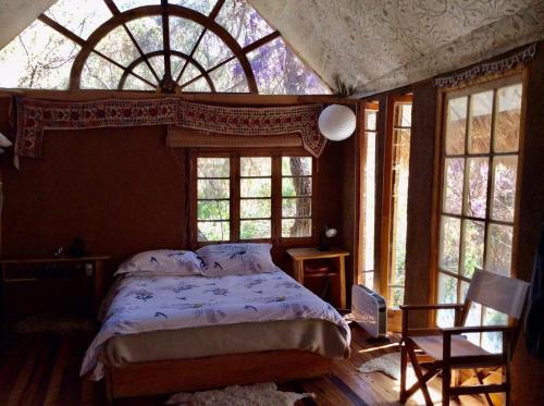 um quarto com uma cama e uma grande janela em La Casa entre los Árboles en el Valle de Elqui Montegrande em Paiguano