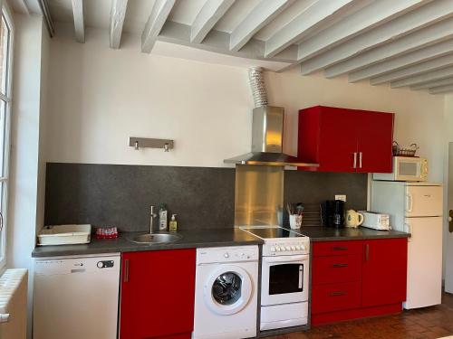 - une cuisine avec des placards rouges et un lave-linge dans l'établissement Gite de la Villa Bois Chaumont, à Brinon-sur-Sauldre