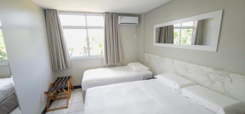 ein weißes Zimmer mit 2 Betten und einem Stuhl in der Unterkunft Hotel - Gran Lençóis 2 suítes in Barreirinhas