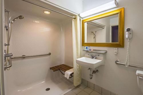 a bathroom with a sink and a shower and a mirror at Royal Inn Suites in Huntington