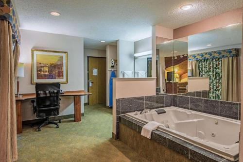 uma ampla casa de banho com uma banheira, uma secretária e um computador em Royal Inn Suites em Huntington