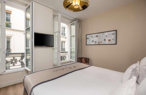 a bedroom with a white bed and two windows at Hôtel Littéraire Arthur Rimbaud, BW Signature Collection in Paris