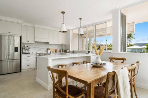 a kitchen with white cabinets and a wooden table and chairs at Designer Retreat Meets Vibrant Beachside Living in Palm Beach