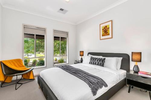 a bedroom with a bed and a desk and windows at Opie's Oasis between West Beach & Henley South in Adelaide