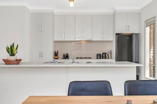 a kitchen with white cabinets and a stainless steel refrigerator at Opie's Oasis between West Beach & Henley South in Adelaide