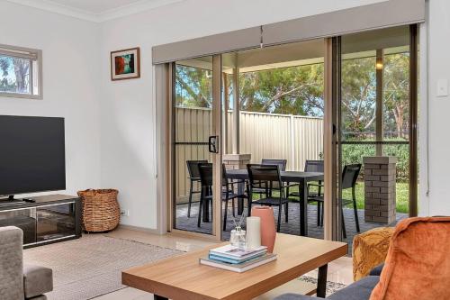 a living room with a television and a table with chairs at Opie's Oasis between West Beach & Henley South in Adelaide